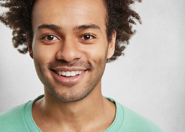 Close up portrait of bearded handsome man with bristle and curly bushy hair, smiles broadly, demonstrates white even teeth, isolated over white background. Happy teenager spends time with friends Close up portrait of bearded handsome man with bristle and curly bushy hair, smiles broadly, demonstrates white even teeth, isolated over white background. Happy teenager spends time with friends