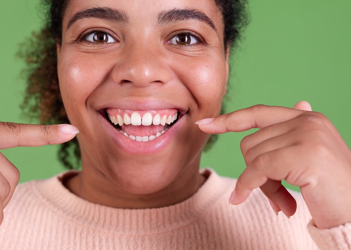 Beautiful african american woman on green background cheerful smiling point index fingers on white teeth smile Beautiful african american woman on green background cheerful smiling point index fingers on white teeth smile