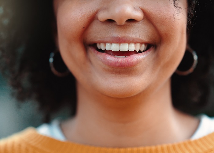 Happy, smile and portrait of an African American woman in an orange sweater with earings.