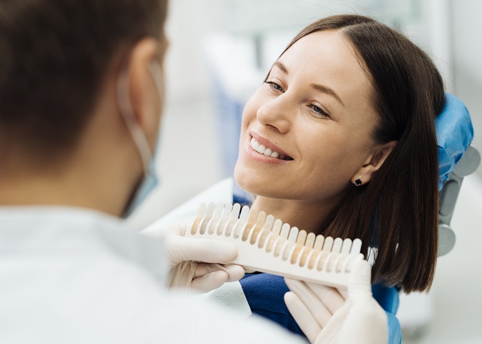 Dentist checking and selecting color of young woman's teeth Dentist checking and selecting color of young woman's teeth