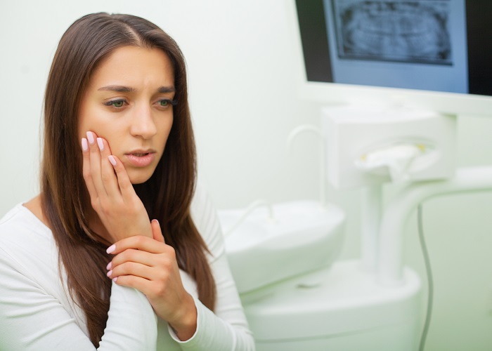 Young female having toothache. Upset woman at the dentist. Constant pulsating pain